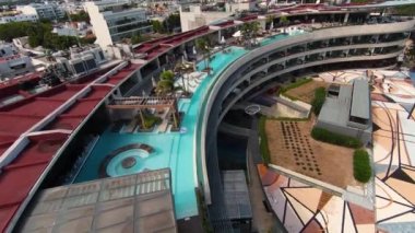 Slow motion drone footage of the large curved rooftop infinity swimming pool and tourists cooling off at the Thompson Playa del Carmen resort, Mexico.