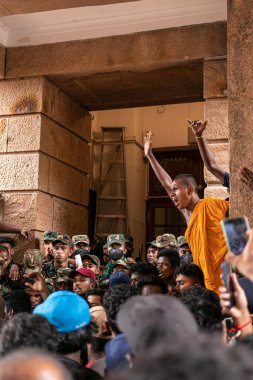 COLOMBO, SRI LANKA: 9th July 2022: Buddhist monk in saffron robe stands over a crowd of angry protestors and soldiers at the Presidential Secretariat.