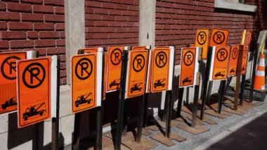 Short clip as camera pans in slow mo showing many parking restriction signposts depicting tow truck on an urban street in downtown Montreal, Canada.