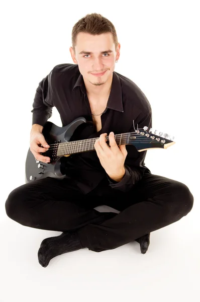 Beautiful guy is playing the electric guitar, sitting on the flo — Stock Photo, Image