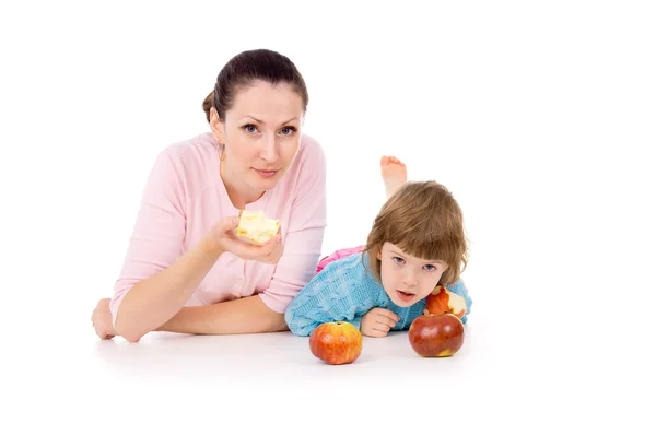 Mère avec un enfant se couche et mange des pommes — Photo