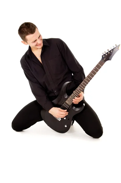 The handsome young man sits and plays the electric guitar — Stock Photo, Image