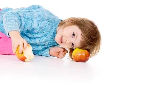 Une belle petite fille couchée à côté des pommes — Photo