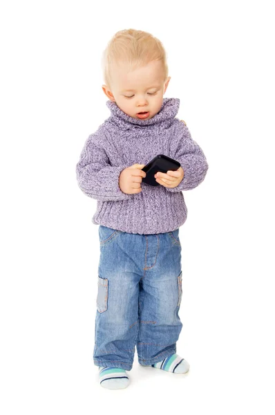 En liten unge spelar med en mobiltelefon — Stockfoto