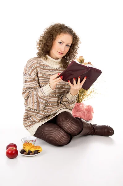 Menina em uma camisola com maçãs e doces e um livro — Fotografia de Stock