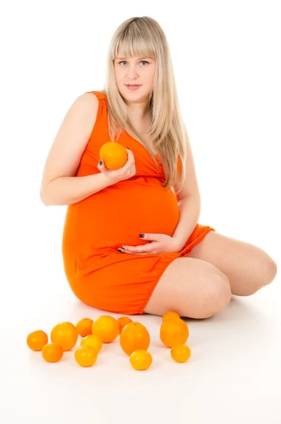 Szczęśliwy w ciąży kobieta siedząca z pomarańczy — Zdjęcie stockowe