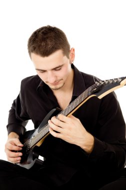 siyah elbise giymiş genç bir adam oturuyor ve gitar çalıyor