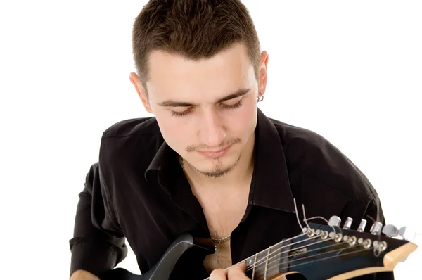 Молодой человек в черной одежде сидит и играет на гитаре — стоковое фото