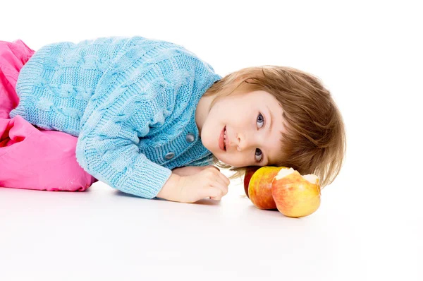 Una bella bambina sdraiata accanto alle mele — Foto Stock