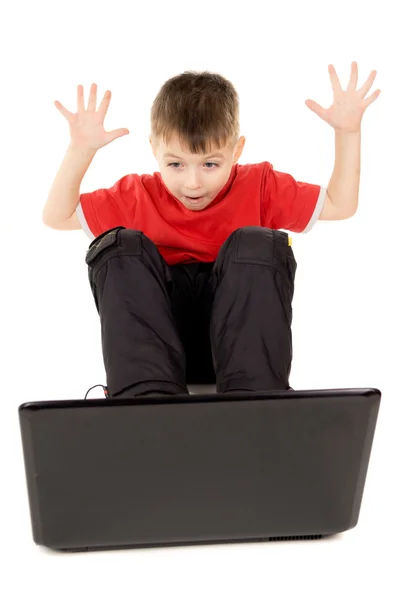 Un bambino piccolo felicemente guardando nel computer notebook, sollevare — Foto Stock