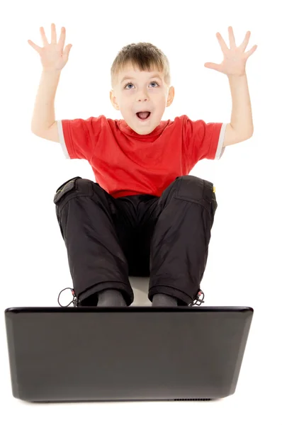 Un bambino piccolo felicemente guardando nel computer notebook, sollevare — Foto Stock