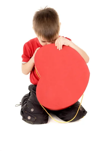 Un bambino piccolo guarda scatola di cartone, sotto forma di cuore — Foto Stock