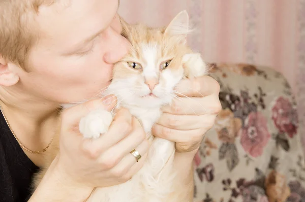 Facet trzyma rudy kot w ramionach — Zdjęcie stockowe