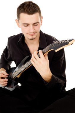 siyah elbise giymiş genç bir adam oturuyor ve gitar çalıyor