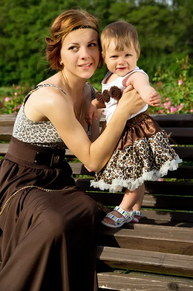 Mãe feliz com um bebê no banco — Fotografia de Stock