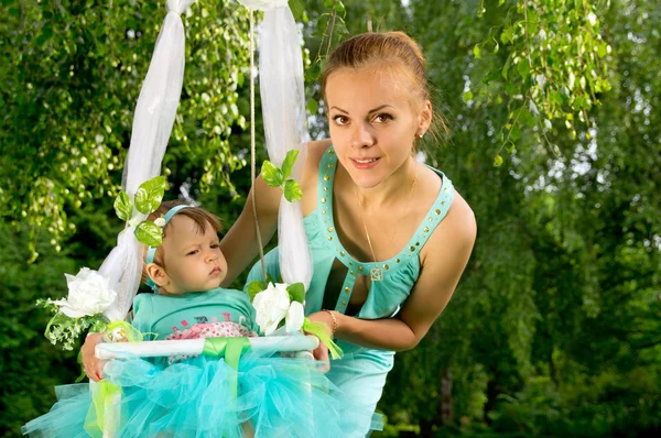 Maman secoue son bébé sur une balançoire sur la nature — Photo
