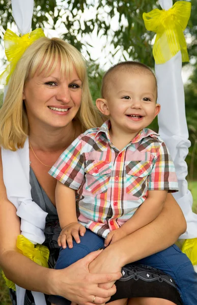 Happy mother 's ride on a swing with son — стоковое фото