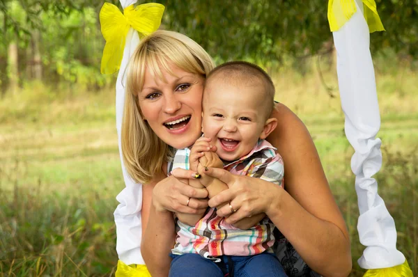 Boldog anyák ride a fiával hinta — Stock Fotó
