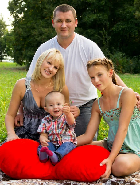 Parents with children lay on the grass and holding a heart — Stock Photo, Image