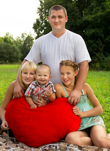 Родители с детьми лежали на траве и держали в руках сердце — стоковое фото