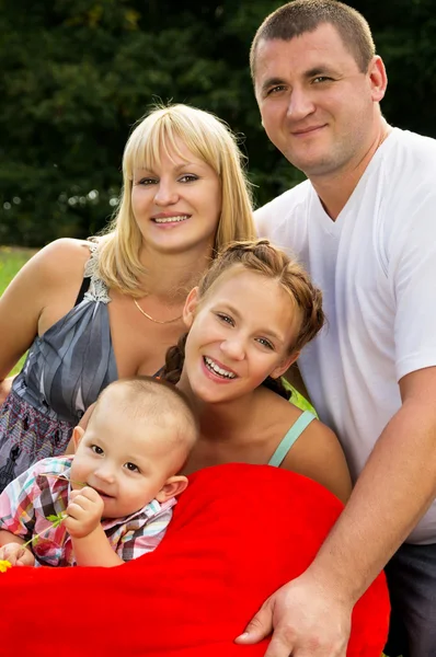 Föräldrar med barn låg på gräset och hålla ett hjärta — Stockfoto