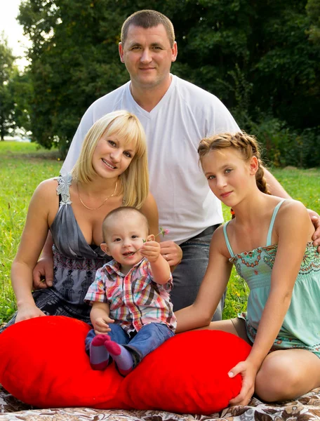 Parents with children lay on the grass and holding a heart Stock Photo