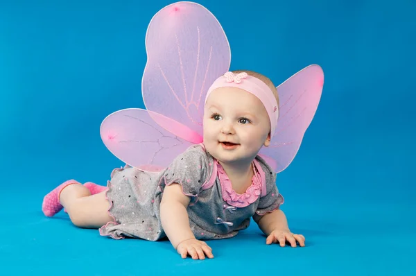 Baby in een jurk liggend op een blauwe pagina — Stockfoto