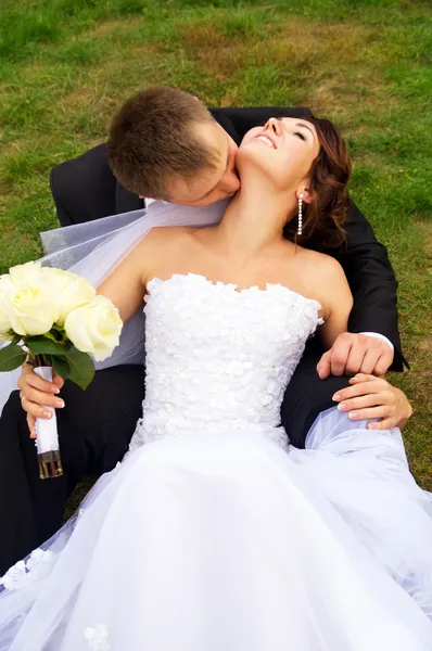 Belos recém-casados jazem na grama — Fotografia de Stock