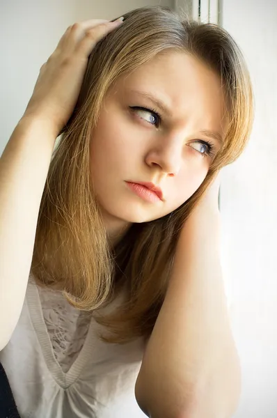 Menina triste olhando pela janela — Fotografia de Stock