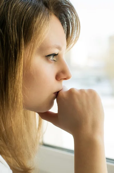 Chica triste mirando por la ventana Imagen de archivo