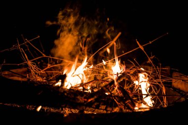 Ateş ve alevler. Alevler ve yanan kıvılcımlar, ateş desenleri. Ateşten gelen alevler. Gece ateşi, odunlar yanıyor, kıvılcımlar uçuşuyor. Yumuşak odaklanma. Sığ odak etkisi.