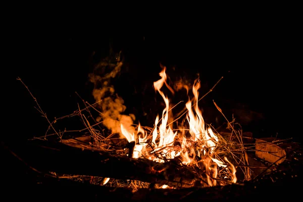 Ateş ve alevler. Alevler ve yanan kıvılcımlar, ateş desenleri. Ateşten gelen alevler. Gece ateşi, odunlar yanıyor, kıvılcımlar uçuşuyor. Yumuşak odaklanma. Sığ odak etkisi.