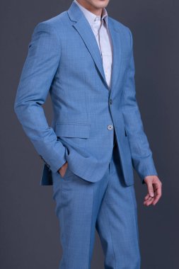 well-dressed senior man in a blue suit in the studio gray background