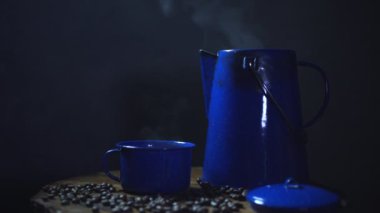 Eski ahşap zeminde kahve çekirdeği ve dumanlı bir bardak mineli kahve. Esrarlı kahve.. 