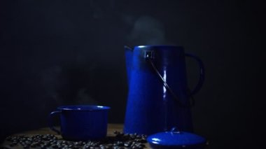 Eski ahşap zeminde kahve çekirdeği ve dumanlı bir bardak mineli kahve. Esrarlı kahve.. 