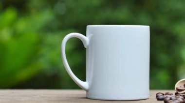 Kahve fincanı ve kahve çekirdekleri eski ahşap bir masada, beyaz seramik bardak..