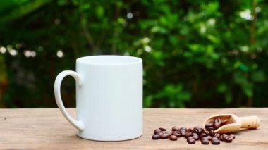 Eski ahşap bir masada kahve fincanı ve kahve çekirdekleri, beyaz bir seramik bardak..
