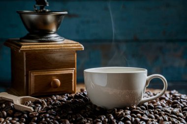 Öğütücüyle kahve fincanı, eski ahşap zeminde koyu kahve çekirdekleri, kahve çekirdekleri. yumuşak odak.                  