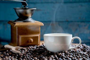 Öğütücüyle kahve fincanı, eski ahşap zeminde koyu kahve çekirdekleri, kahve çekirdekleri. yumuşak odak.                  