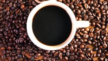 Bardakta sade kahve, eski ahşap zeminde koyu kahve çekirdekleri, kahve çekirdeklerini yakın..