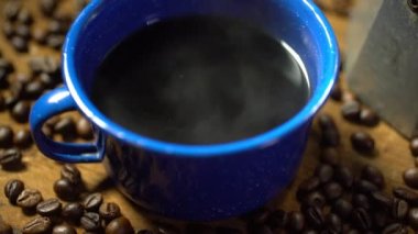 Eski ahşap zeminde kahve çekirdeği ve dumanlı bir bardak mineli kahve. Esrarlı kahve seti. yumuşak odak.