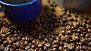 Eski ahşap zeminde kahve çekirdeği ve dumanlı bir bardak mineli kahve. Esrarlı kahve seti. yumuşak odak.