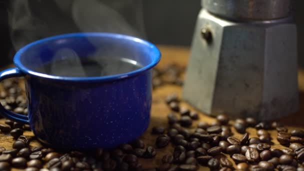Kaffeebohnen auf dem alten Holzboden und eine Emaille-Tasse Kaffee mit Rauch. Kaffeesatz mit Kanne vorhanden. Weicher Fokus.