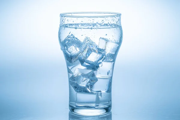 氷の立方体が水のガラスの中に落ち込み 透明なガラスから水が飛び散った — ストック写真