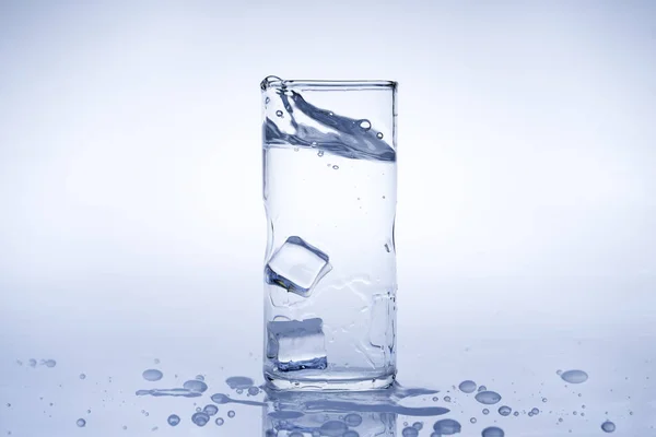 冰块掉进水杯里去了 水从透明的杯子里溅了出来 — 图库照片