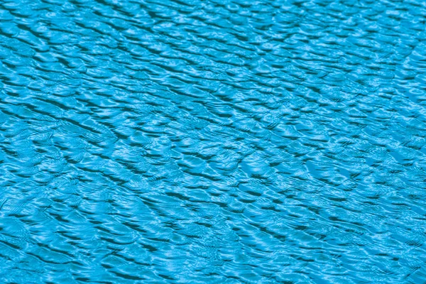 bluewater surface By the wind. The water surface was ruffled by the light wind with small waves running diagonally, with reflections and graduated from light and blue tones. soft focus.