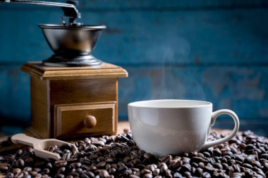 Öğütücüyle kahve fincanı, eski ahşap zeminde koyu kahve çekirdekleri, kahve çekirdekleri. yumuşak odak.                  