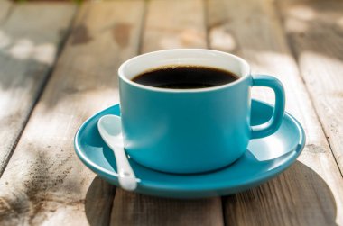 Eski ahşap zeminde mavi seramik kahve fincanı. Yumuşak odaklanma. Sığ odak etkisi.