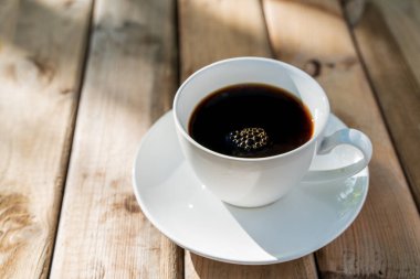 Eski ahşap zeminde beyaz seramik kahve fincanı. Yumuşak odaklanma. Sığ odak etkisi.