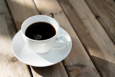 Eski ahşap zeminde beyaz seramik kahve fincanı. Yumuşak odaklanma. Sığ odak etkisi.